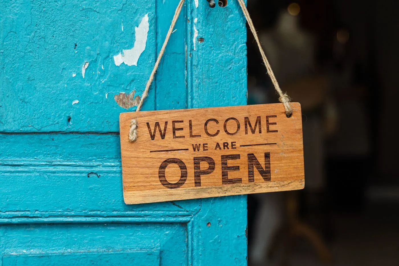 ドアに掛かった「WELCOME WE ARE OPEN」の木の看板